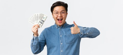 Excited smiling asian man with braces and glasses showing thumbsup